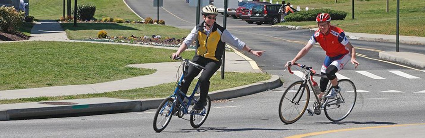People riding bicycles through a marked street crossing, reflecting safer district travel routes